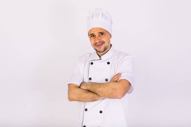 istock Chef cook wearing cooking jacket and hat, arms crossed, on white background 1356462128