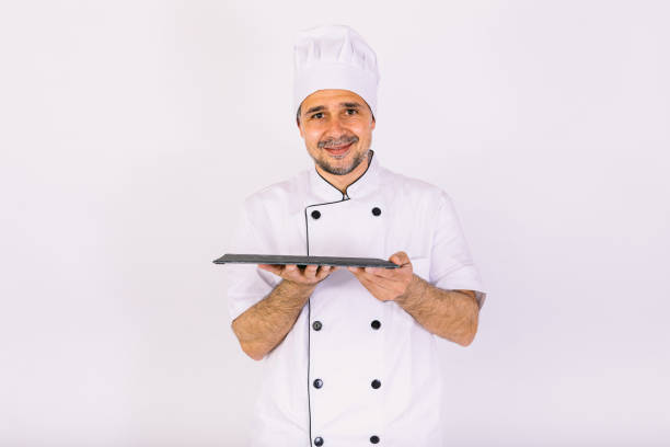 istock Chef cook wearing kitchen jacket and hat, holding a wooden tray, on white background 1356462225
