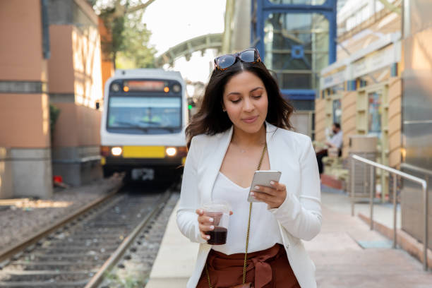 Woman using smartphone at train station stock photo