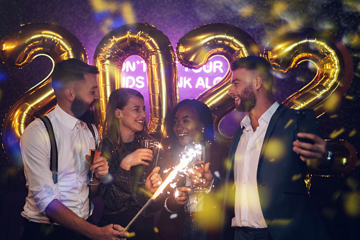 Happy group of friends celebrate New Year's Eve while drinking campaign on a party in a club and taking selfie with a smartphone
