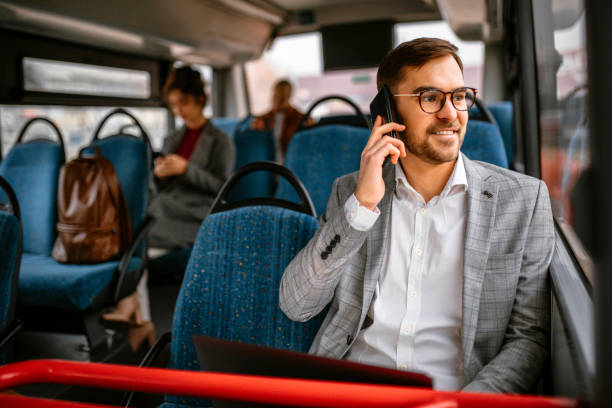 businessman riding in public transportation on his way to the office - bus riding public transportation businessman imagens e fotografias de stock