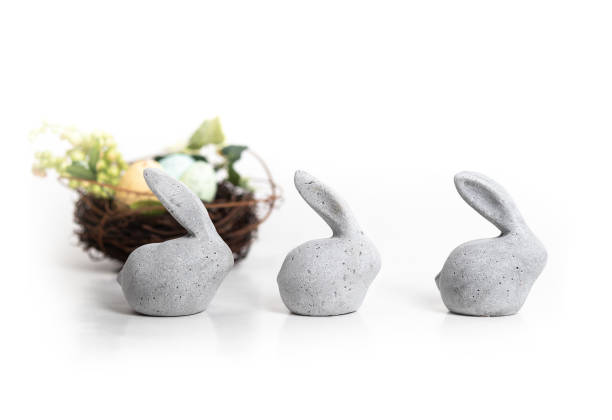 istock Three small stone rabbits with defocused bird nest and greenery. 1356474862