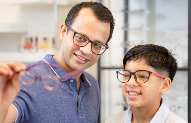 Indian father and son choosing eyeglasses in optics store