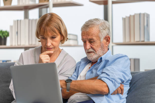 istock Worried senior couple checking their bills and work on netbook read document information at home, retired elderly old family reading documents with laptop 1356479113