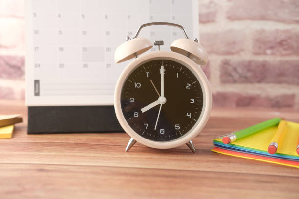 istock old alarm clock and calendar on wooden background. 1356479973