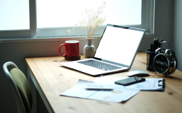 istock Laptop computer with blank screen, coffee cup, clipboard and pencil holder on wooden desk. 1356481049