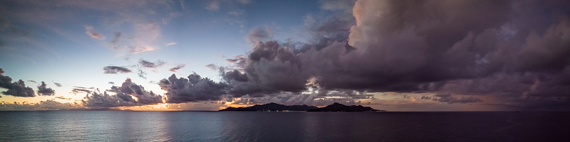 Seychelles Praslin Island Dramatic Sunset Panorama. Sun setting over Praslin Island with moody, dramatic storm and thunderbolt clouds. Stiched XXXXL Drone Flight Panorama. Drone view from La Digue Island over the Indian Ocean. Praslin Island, Seychelles, East Africa, Africa.