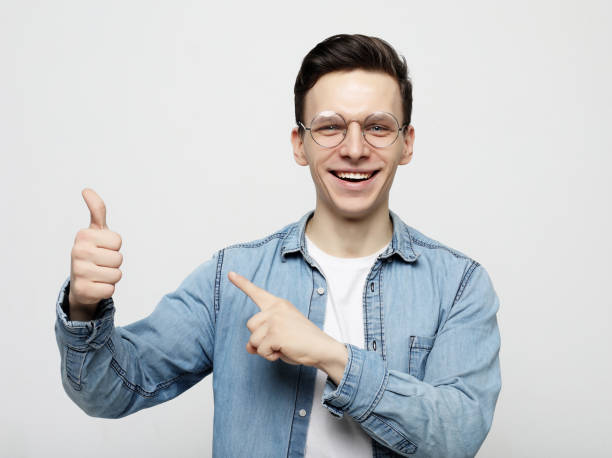istock Positive man looks and points at upper right corner with both index fingers 1356484334