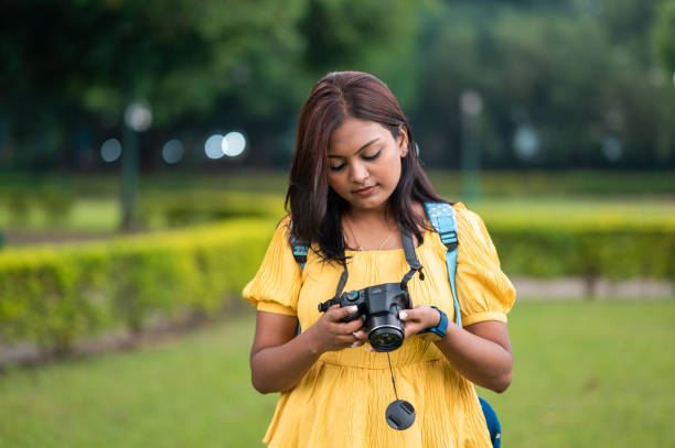istock Beautiful young girl holding a camera in her hands and watching it. 1356487158