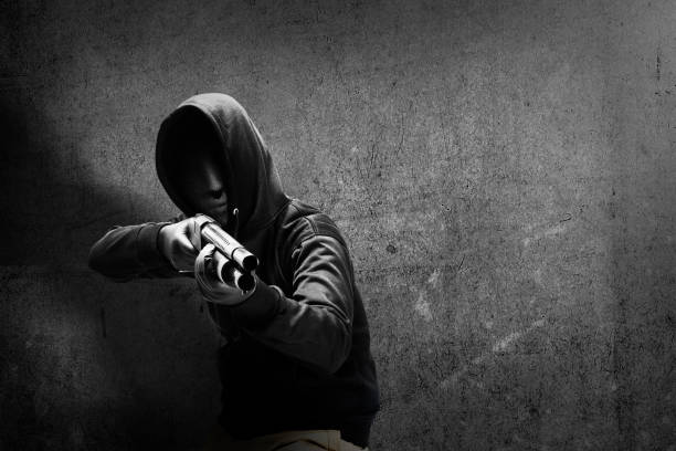 istock Criminal man in hidden mask pointing the shotgun 1356495080