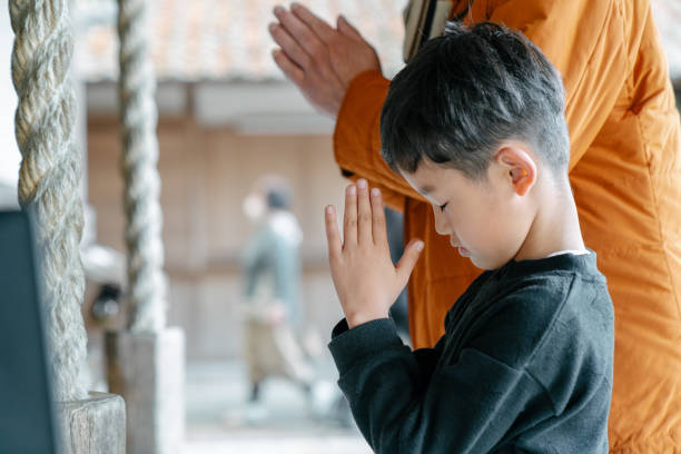 Young boy praying with his grandfather at a Japanese temple Young boy praying with his grandfather at a Japanese temple. Okayama, Japan shrine photos stock pictures, royalty-free photos & images