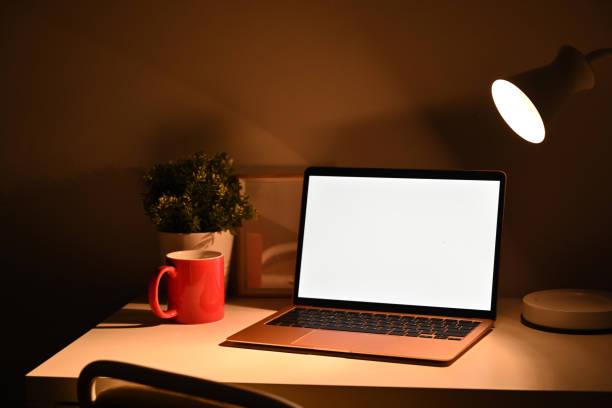 istock Computer laptop, red cup and lamp in dark room. 1356496088