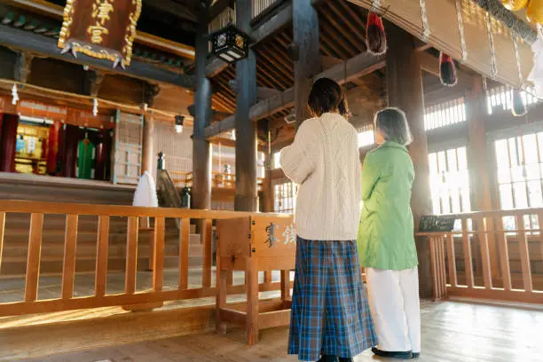 Senior woman and her daughter praying at a Japanese temple for Hatsumode. Okayama, Japan