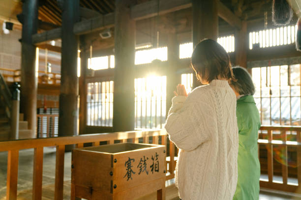 une femme âgée et sa fille prient dans un temple japonais pour hatsumode - shintoïsme photos et images de collection