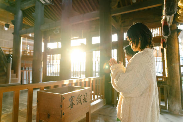 senior woman and her daughter praying at a japanese temple for hatsumode - winter women zen like photography imagens e fotografias de stock