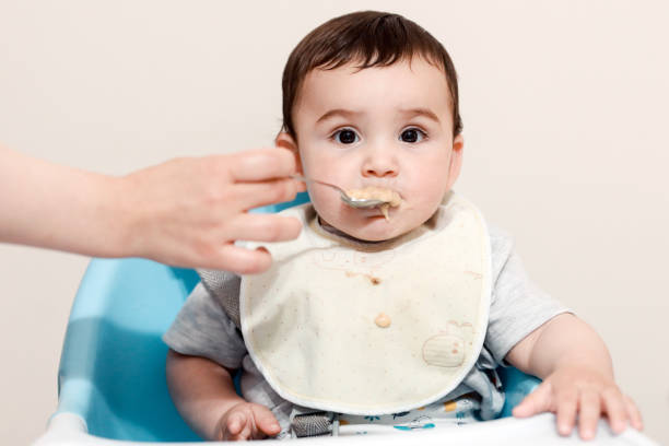 istock Baby child eating with spoon with mother 1356500627