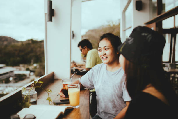 istock asian woman taking drink and talking in cafe 1356501772