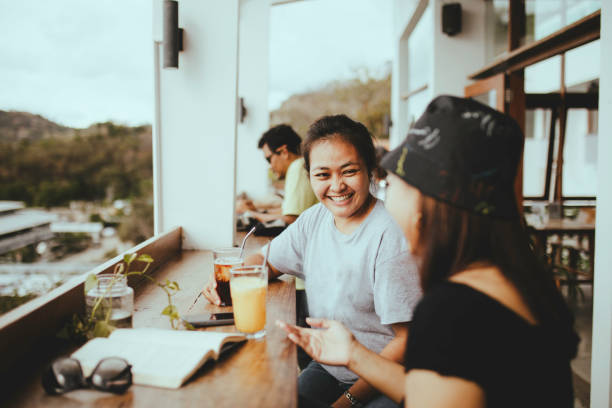 istock asian woman taking drink and talking in cafe 1356501776