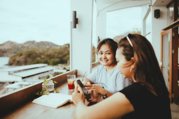 istock asian woman taking drink and talking in cafe 1356501807
