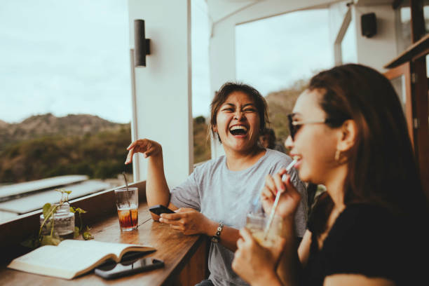 asian woman taking drink and talking in cafe