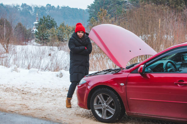 istock woman looking at engine broken car at winter road side 1356502603