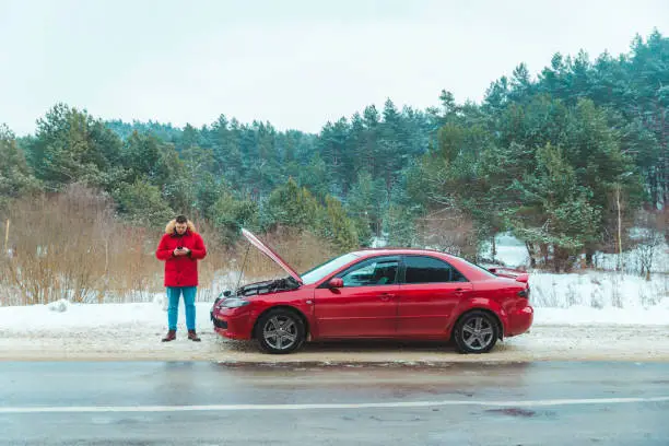 Photo of man standing near broken car at roadside snowed winter weather