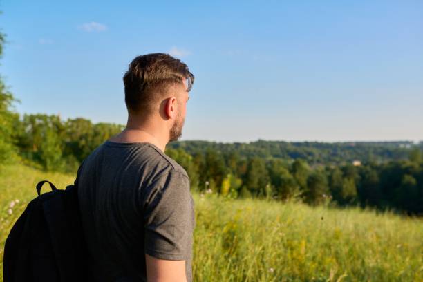 istock Middle-aged bearded man with a backpack on a hike looking at the horizon 1356504578