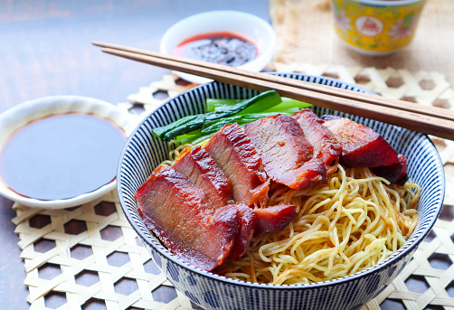 Honey barbecue grilled pork on top with egg noodles with soy sauce and vegetable.