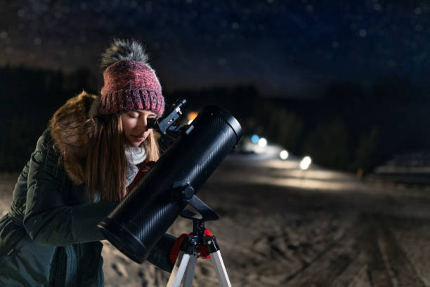 teenage girl observing the winter night sky with telescope - olhando através imagens e fotografias de stock