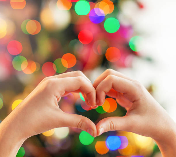 istock Heart from the hands in front of christmas tree 1356509332
