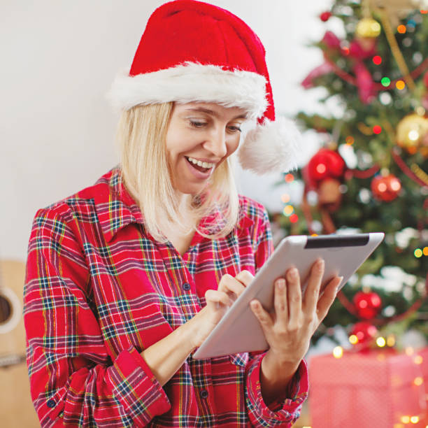 istock Woman using tablet in front of christmas tree 1356509717