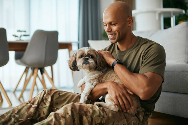 glücklicher schwarzer soldat, der mit seinem hund genießt, nachdem er vom einsatz nach hause gekommen ist. - schoßhund stock-fotos und bilder