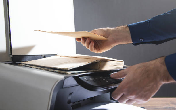 istock Man copying a book on a copy machine. 1356515494