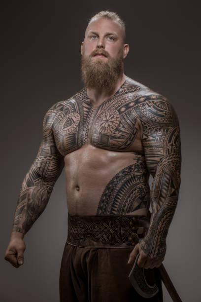 A young tattooed man in a casual outfit standing outside