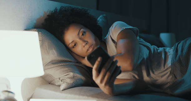 African american woman checking her phone at night stock photo
