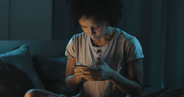 istock African american woman checking her phone at night 1356524558