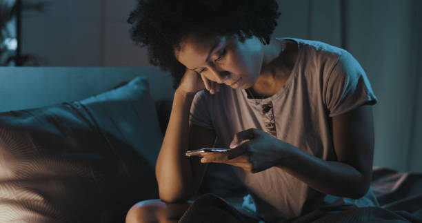 istock African american woman checking her phone at night 1356524677