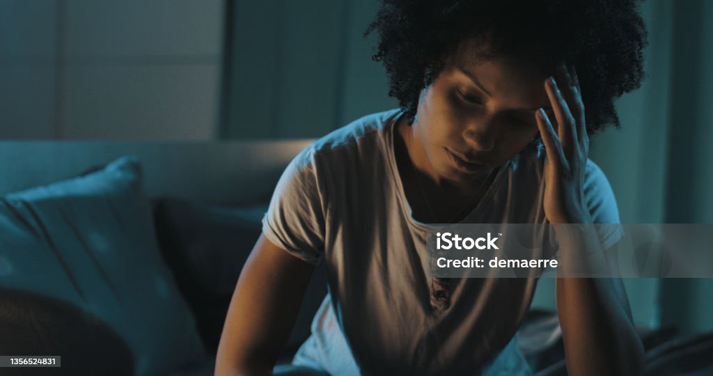 Depressed woman suffering from insomnia Depressed african american woman sitting on bed, she is suffering from insomnia Insomnia Stock Photo