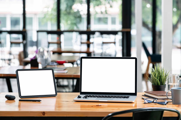 istock Blank screen tablet and laptop computer on wooden table in co-workspace. 1356524976