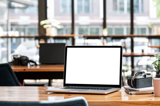 istock Mockup blank white screen laptop computer on wooden table in co-workspace. 1356525069