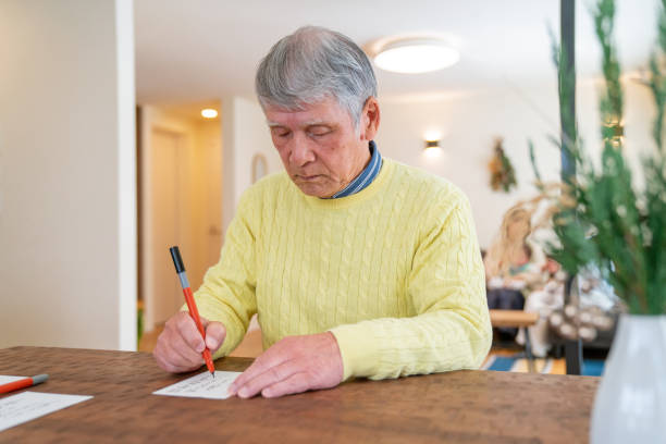 istock Senior Japanese man writing a New Years card 1356525083
