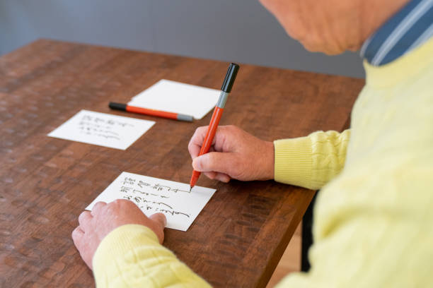 Senior Japanese man writing a New Years card