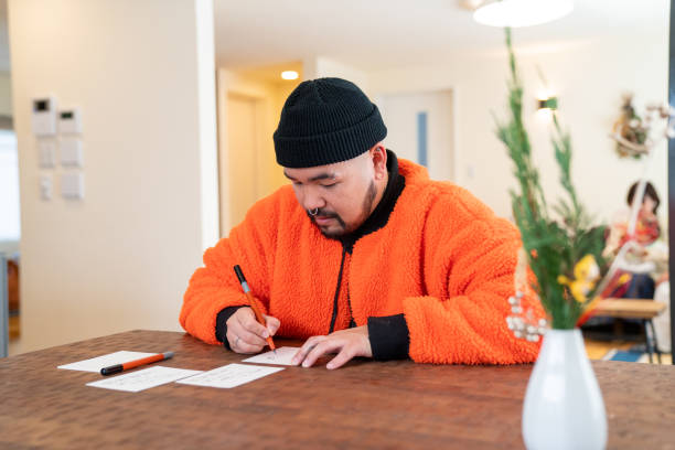 young japanese male writing a new years card - tattoo japanese culture women asian ethnicity imagens e fotografias de stock