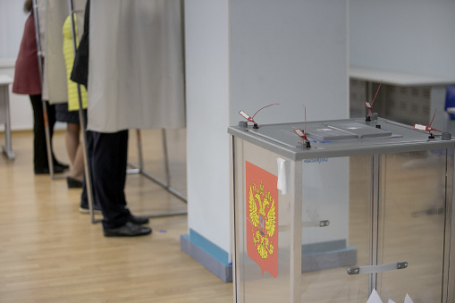 Ballot boxes for elections with the emblem of Russia at a polling station.