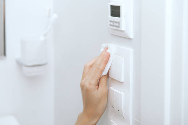 istock Cleaning switches and sockets with a microfiber cloth. Sanitize surfaces prevention in hospital and public spaces against corona virus. Woman hand using wet wipe for cleaning home room door link 1356526653