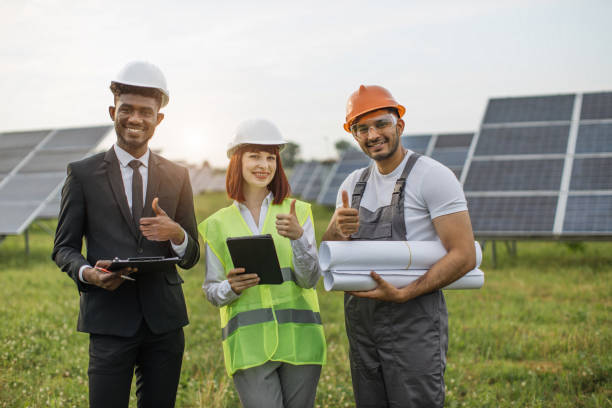 istock Multi ethnic people in helmets posing on solar farm, smiling with thumbs up 1356528487