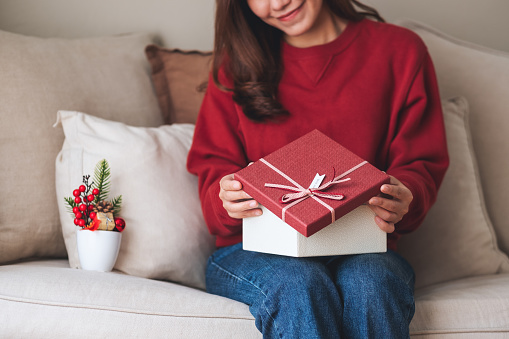 Closeup image of a young woman opening a gift box