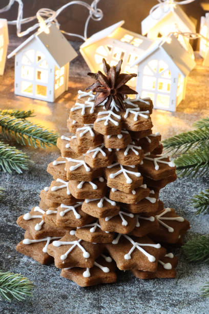 スターアニスをトッピングした積み重ねられたジンジャーブレッドスノーフレークビスケットから形成されたクリスマスツリーのクローズアップ画像は、白い王室のアイシングで飾られ、ト� - star shape christmas ornament heap stack ストックフォトと画像