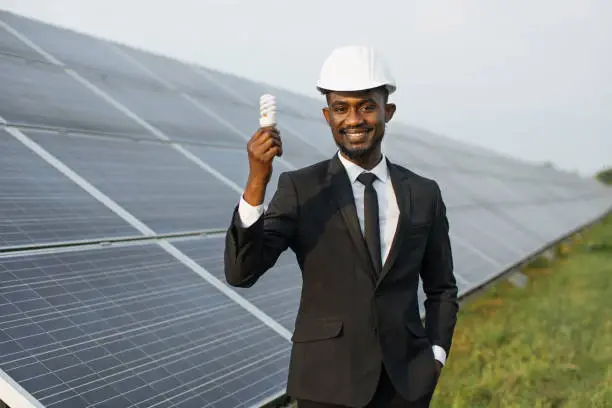Photo of African american man standing at solar farm with bulb