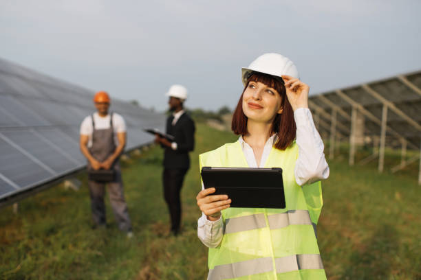 istock Woman in helmet with tablet standing at solar station 1356531059